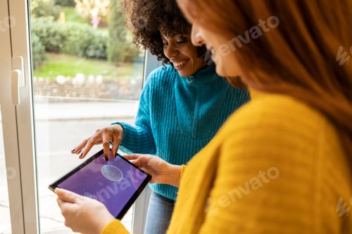 Preview: Close view of multiracial lesbian couple living in a smart house using a tablet for home automation.