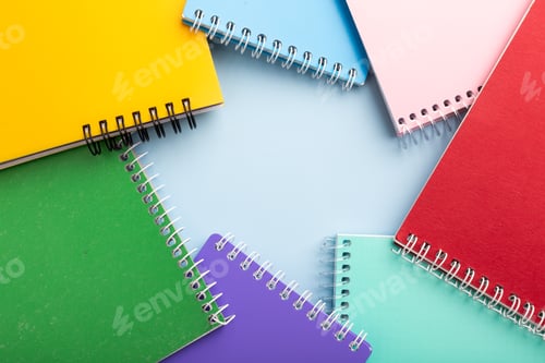 Preview: colored notebooks, colored pencils on a light table. Place for your text.