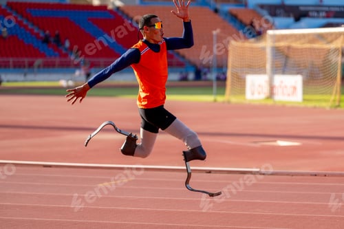 Preview: Asian para-athletes with prosthetic blades sprint on a running track at stadium.