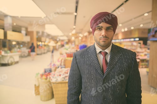 Preview: Young handsome Indian Sikh businessman wearing turban while exploring the city