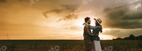 Preview: beautiful couple embracing on meadow at sunset