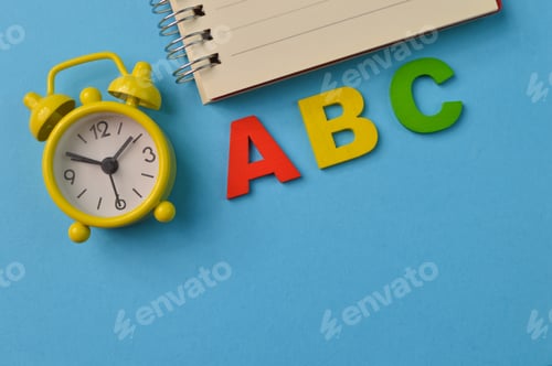 Preview: Clock, notebook and ABC letters isolated on a blue background with copy space