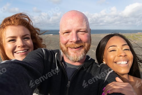 Preview: Three people smiling together at the ocean beach
