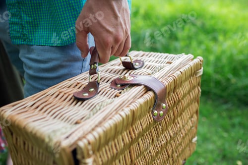 Preview: A man's hand holding a wicker picnic basket.