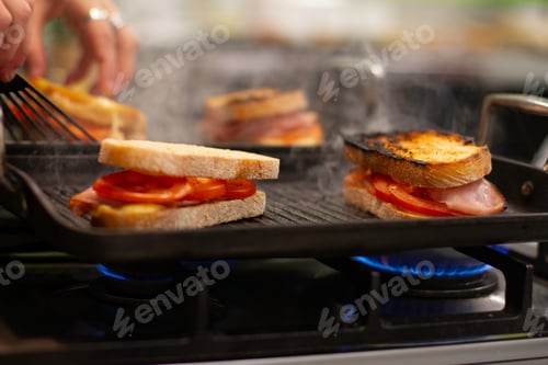 Preview: Grilled ham, cheese and tomato sandwiches being toasted on a gas grill/ bbq in the kitchen