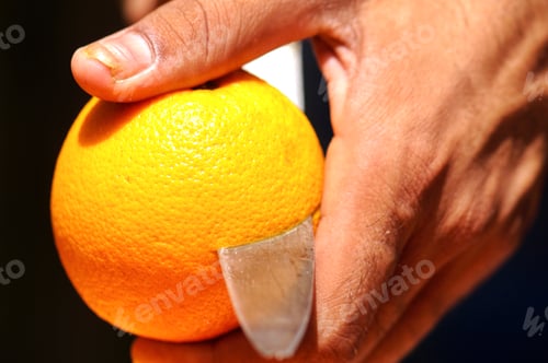Preview: A diverse unrecognizable person slices a fresh organically grown orange to make orange juice