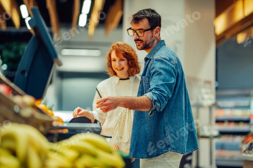 Preview: Couple weighing fresh produce at supermarket checkout, embracing healthy lifestyle