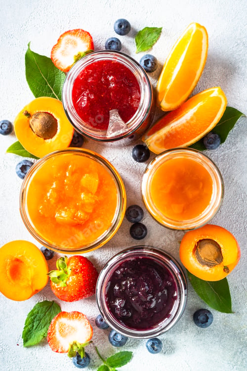 Preview: Homemade jam in glass jars at white table.