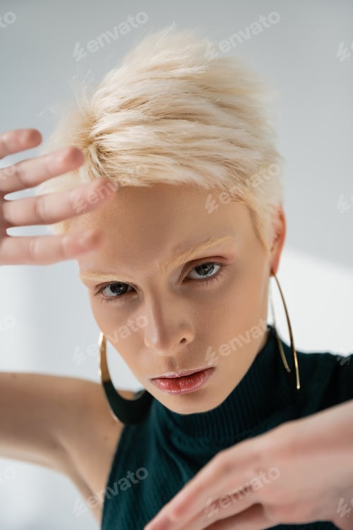 Preview: portrait of young woman with fair-skin gesturing while looking at camera on grey background