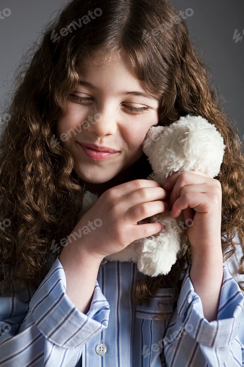 Preview: Young girl cherishing a moment with her soft, white teddy bear