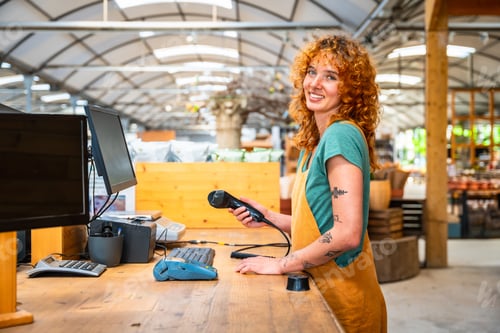 Preview: Saleswoman holding barcode scanner at checkout counter in garden center