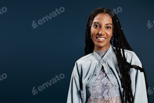 Preview: Stylish young woman with long braids smiles in a modern studio setting on a vibrant backdrop