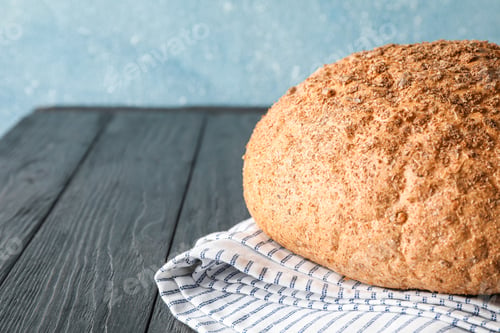Preview: Bread on kitchen towel on wooden table against light background, space for text and closeup