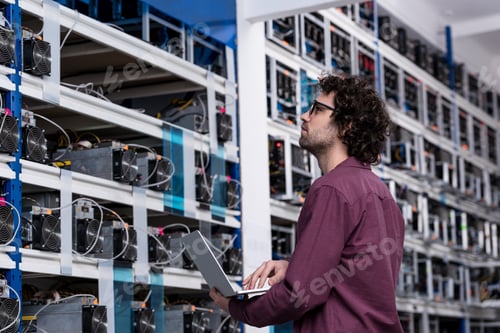 Vista previa: ingeniero informático trabajando con una computadora portátil en una granja minera de criptomonedas