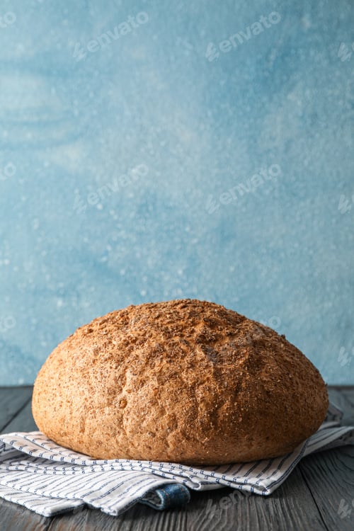 Preview: Bread on kitchen towel on wooden table against light background, space for text