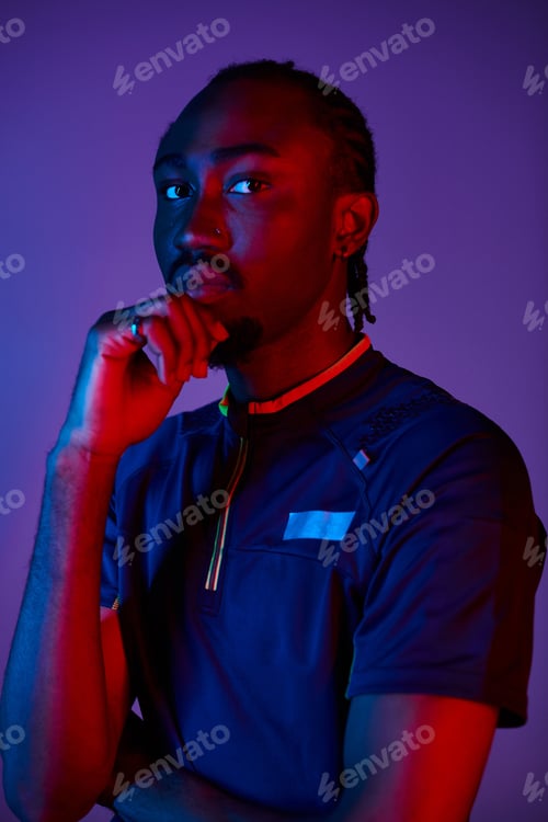 Preview: Young Black man in stylish clothes poses confidently in a vibrant neon studio