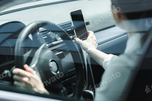 Preview: Selective focus of businesswoman holding smartphone while driving car