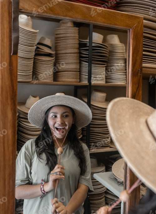 Preview: A young Hispanic woman is looking in the mirror trying a new hat