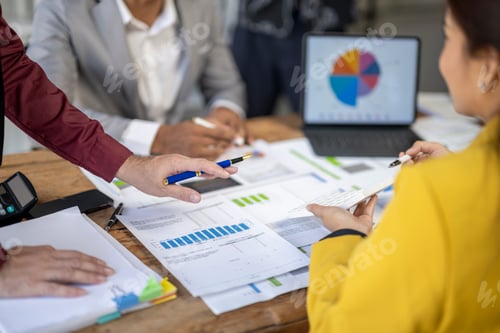 Preview: A group of people are sitting around a table with papers and a laptop.