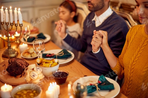 Preview: Close-up of Jewish family praying at dining table during Hanukkah.