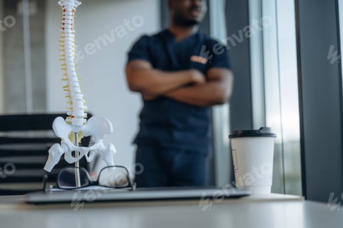 Preview: Standing, the model of human spine, back. Professional doctor is in his office indoors