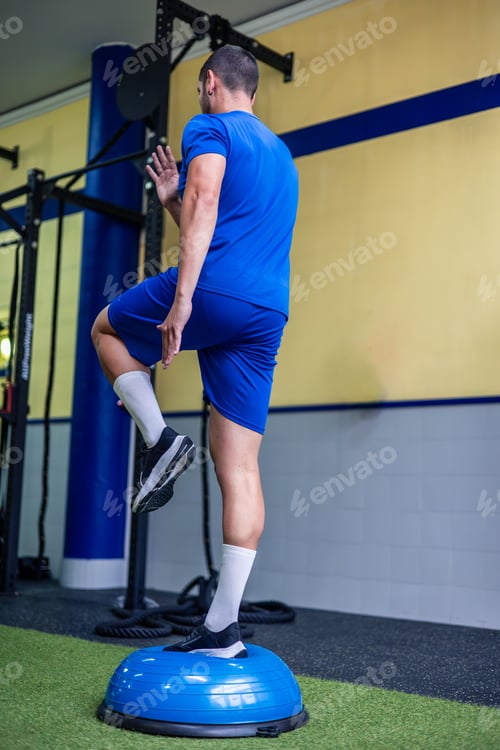 Preview: vertical athlete doing leg strength and balance exercises with Bosu ball during crossfit training