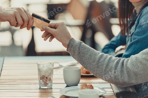 Preview: cropped shot of couple paying with credit card in cafe