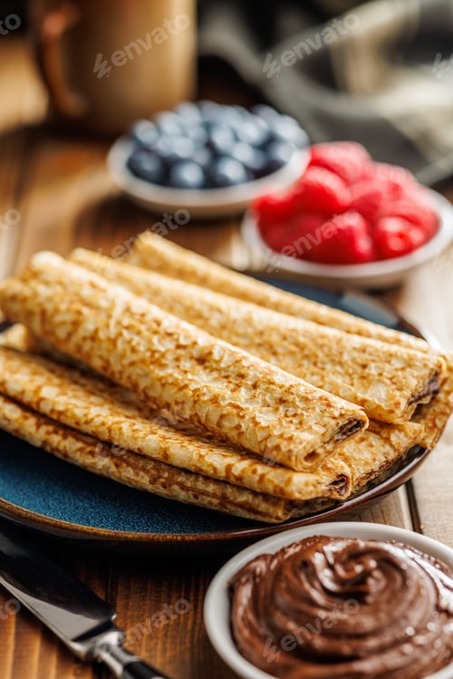 Preview: Freshly Made Golden Crepes Stacked on a Plate, Ready for Breakfast