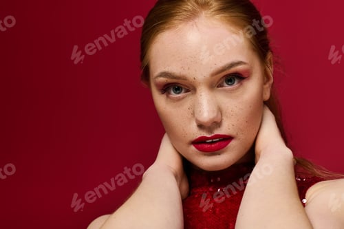 Preview: Young woman exuding confidence with striking makeup against a bold red background
