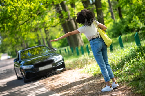 Preview: Hitchhiking. Curly-haired young girl hitchhiking and looking excited