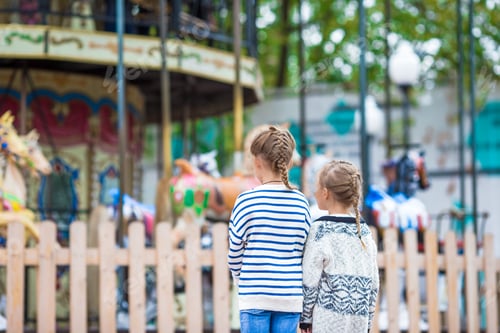 Preview: Adorable little girls near the carousel outdoors