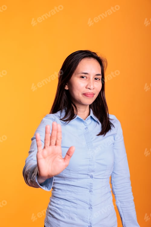 Preview: Serious filipino woman raising palm to advertise stop gesture
