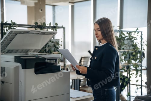 Preview: Working with printer. Beautiful woman is in the office
