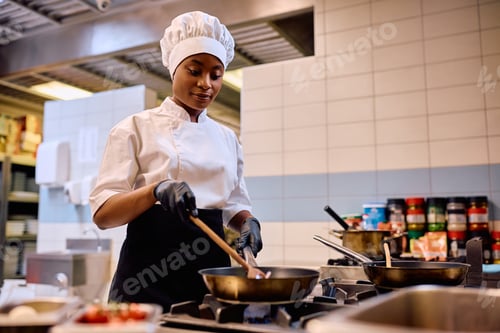 Preview: Black female chef cooking while working in the kitchen in a restaurant.