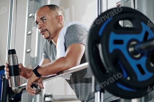 Preview: Mature man leaning on barbell