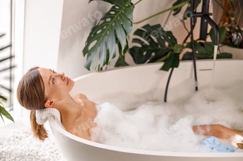 Preview: Relaxed young woman bathing while spending time indoors at luxury spa resort