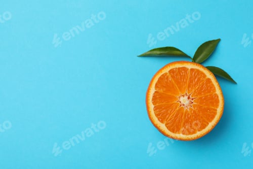 Preview: Half of mandarin with leaves on blue background Half of mandarin with leaves on blue background