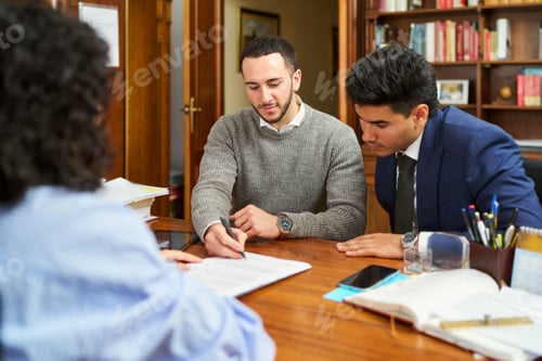 Preview: Three people are sitting at a table with papers and a pen