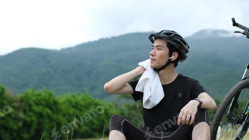 Preview: Tired man with artificial wipe sweat cycling. shot of exhausted sportsman standing with bicycle in