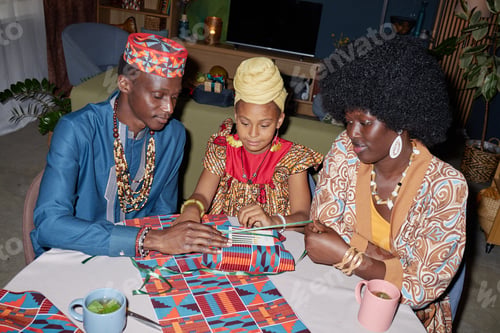 Vista previa: Black Family Celebrating Kwanzaa with Young Girl Lighting Kinara Candles