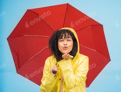 Preview: Woman, portrait or blowing kiss and rain umbrella on isolated blue background in Brazil city love o