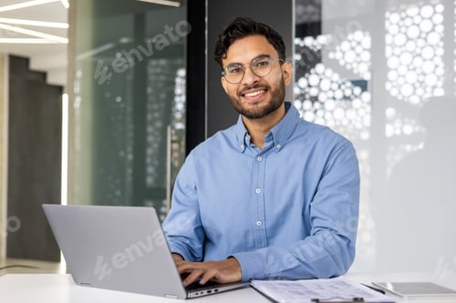 Preview: Portrait of young successful businessman inside office, satisfied joyful Indian man looking at