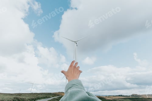 Preview: Human hand reaching Wind Turbines Windmill Energy on the nature, during a super sunny day