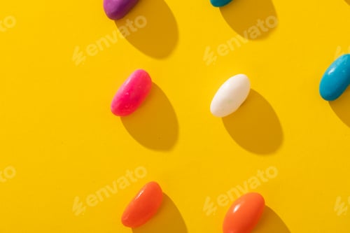 Preview: Overhead view of fresh multi colored candies arranged in a row on yellow background