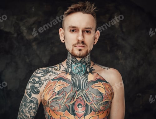 Preview: Naked tattooed hipster poses in dark background looking at camera