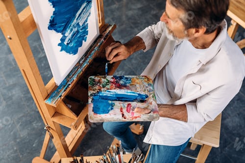 Preview: High angle view of male artist holding palette and paint knife
