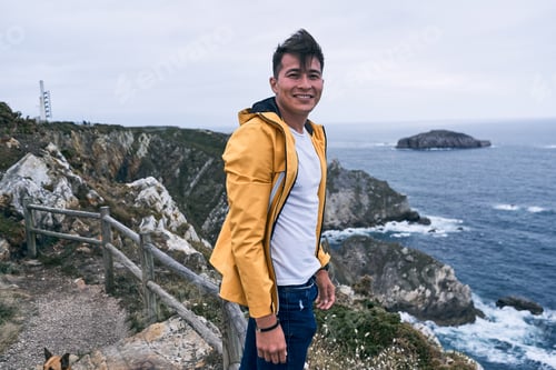 Preview: latin young man in white t-shirt and yellow jacket smiling looking at camera calm and relaxed