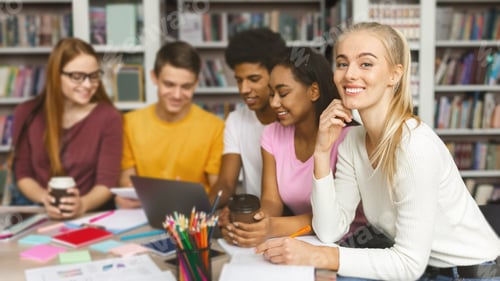 Preview: Cheerful college students studying together in library