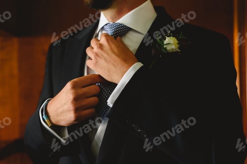 Preview: Hands of groom knotting his tie to the bridal fashion before going to the ceremony.