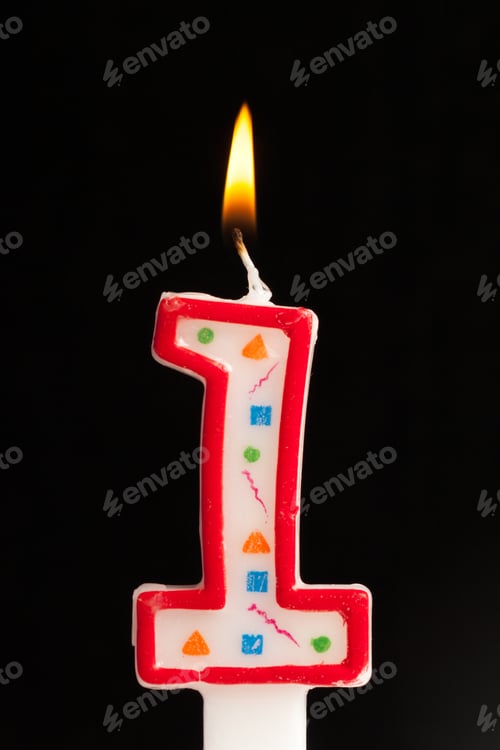 Preview: Birthday celebration with a colorful number one candle glowing brightly in the dark
